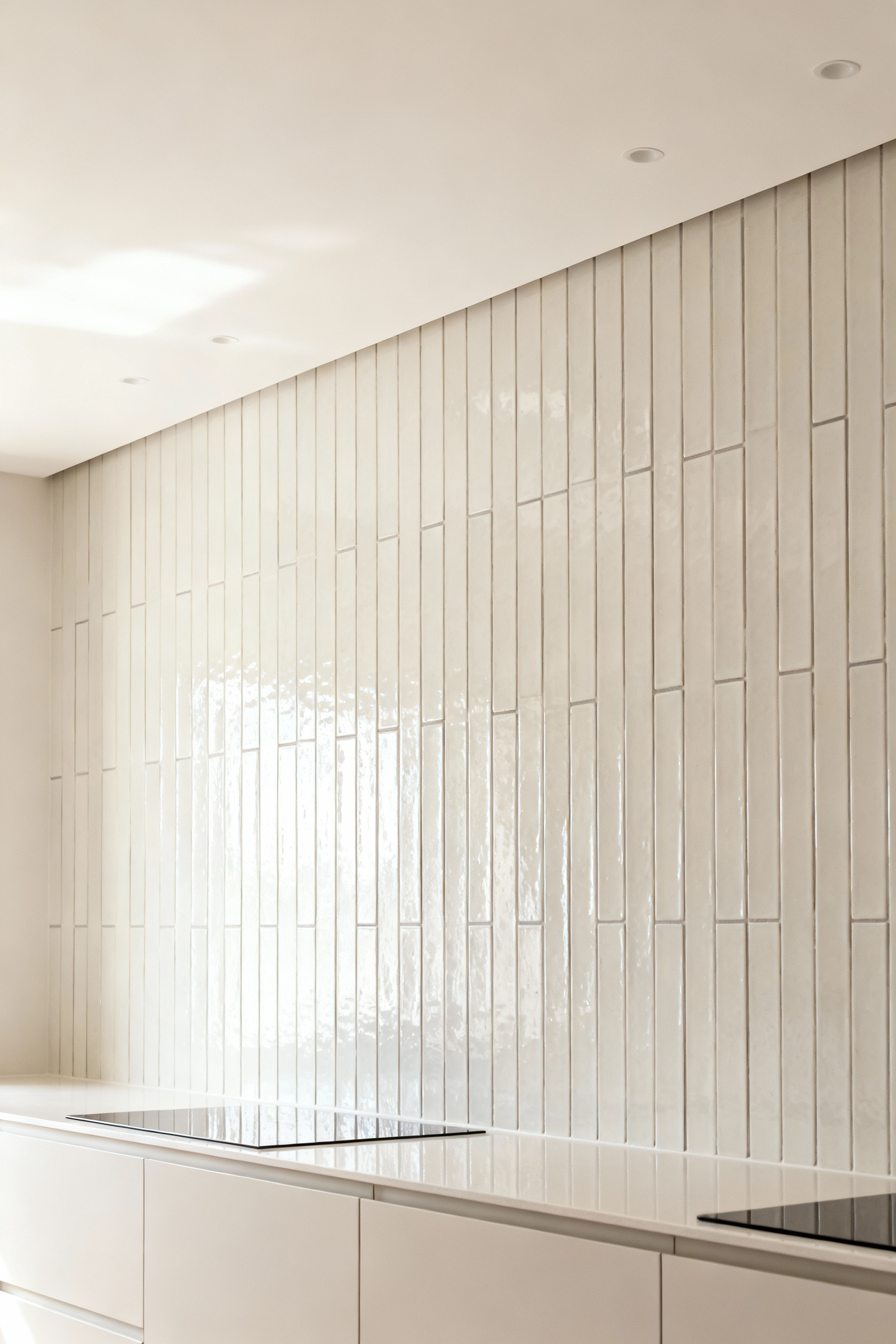 Modern kitchen with a floor-to-ceiling backsplash of vertically oriented light ceramic tiles, creating an illusion of greater room height. The sleek design enhances the perception of an elevated ceiling in the kitchen.