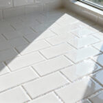 Close-up of sparkling white subway tiles with perfectly clean and whitened grout lines in a brightly lit, modern bathroom, showcasing a pristine and refreshed appearance.