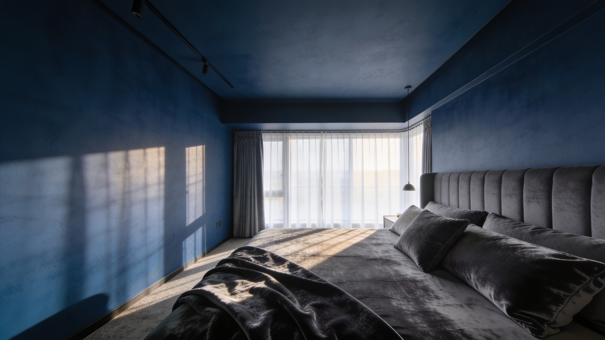 A high-end bedroom interior featuring a deep midnight blue and charcoal paint scheme designed for emotional relaxation and neuro-aesthetic appeal.