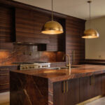 Detailed image of a luxurious kitchen featuring floor-to-ceiling walnut cabinetry and a dark marble island, emphasizing warm espresso and cocoa tones for a grounding, biophilic design.
